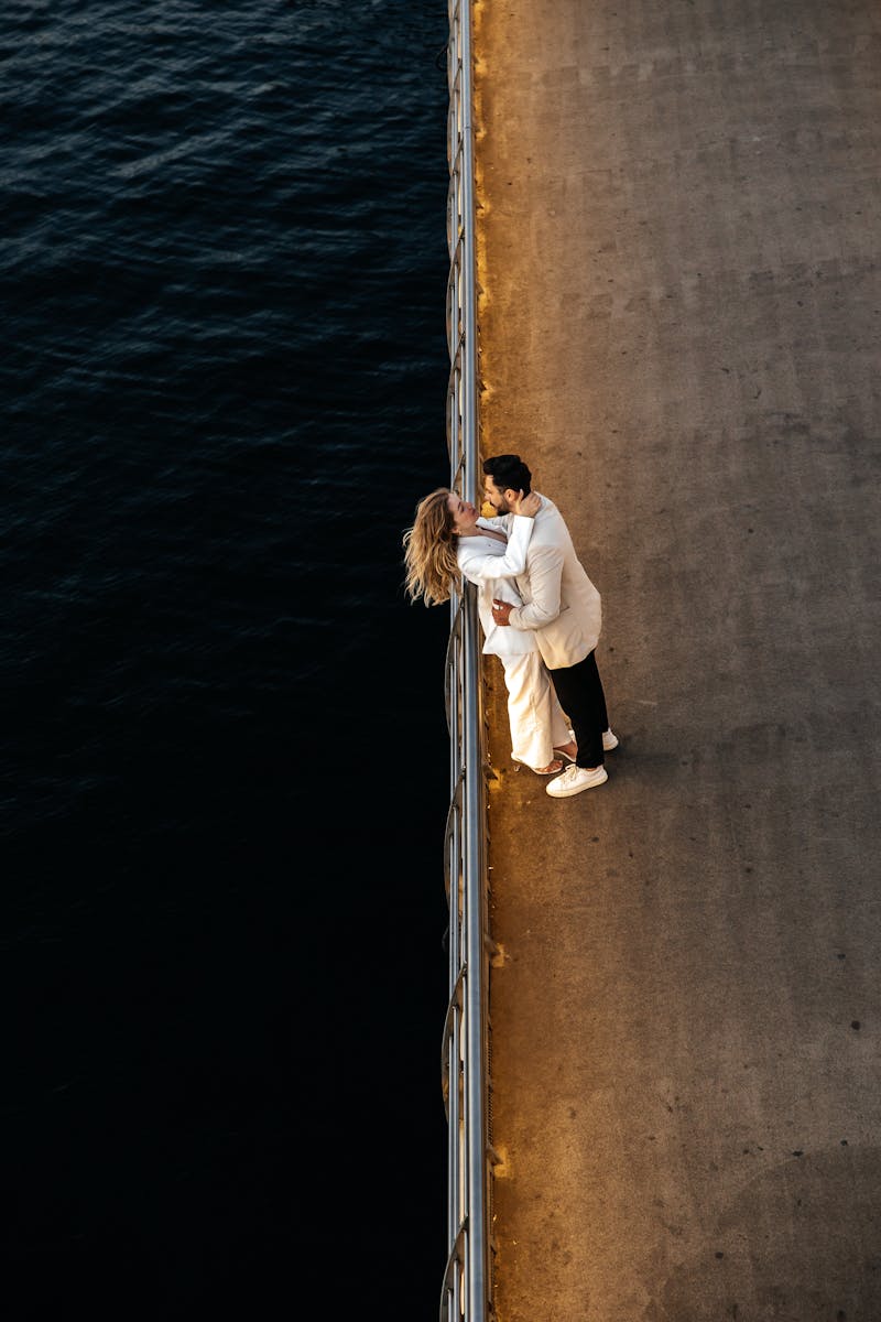 A couple embraces romantically on a sunset-lit seaside promenade in Türkiye, offering a serene and intimate moment.